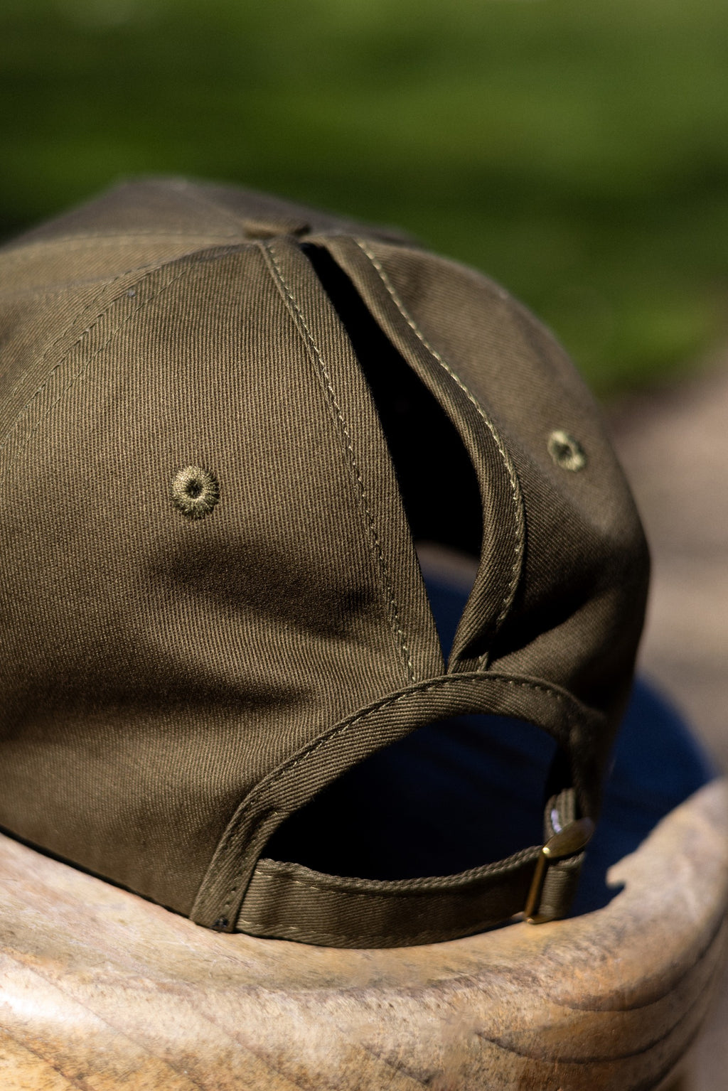 Back of the Olive FOKE cap showing separate high and low ponytail openings and the adjustable strap.