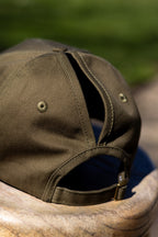 Back of the Olive FOKE cap showing separate high and low ponytail openings and the adjustable strap.