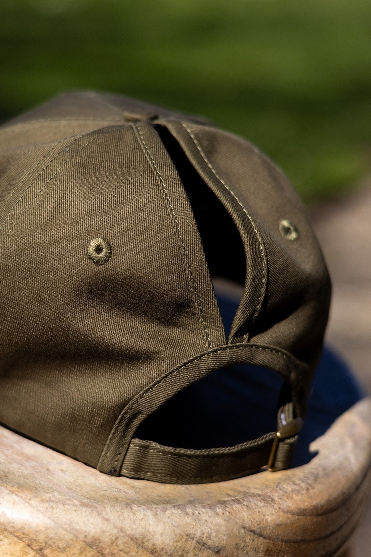 Back of the Olive FOKE cap showing separate high and low ponytail openings and the adjustable strap.
