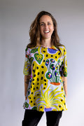 Woman wearing a colourful yellow FOKE artist tee with original hand-drawn print, front view.