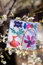 FOKE temporary tattoo sheet with a pink flower, orange vase and colourful shapes displayed among blossoms.