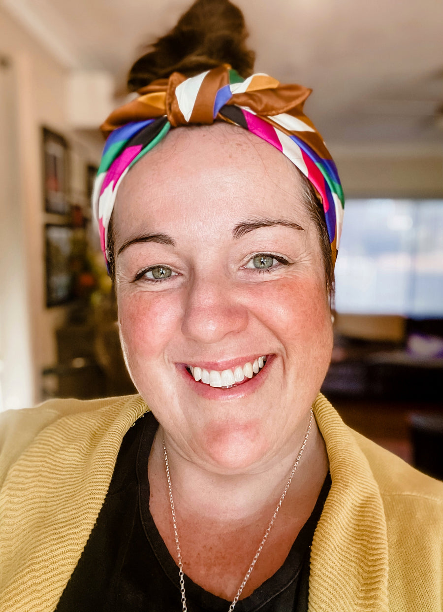 Holly Clinton, founder and artist of FOKE, smiling in a colourful printed headscarf