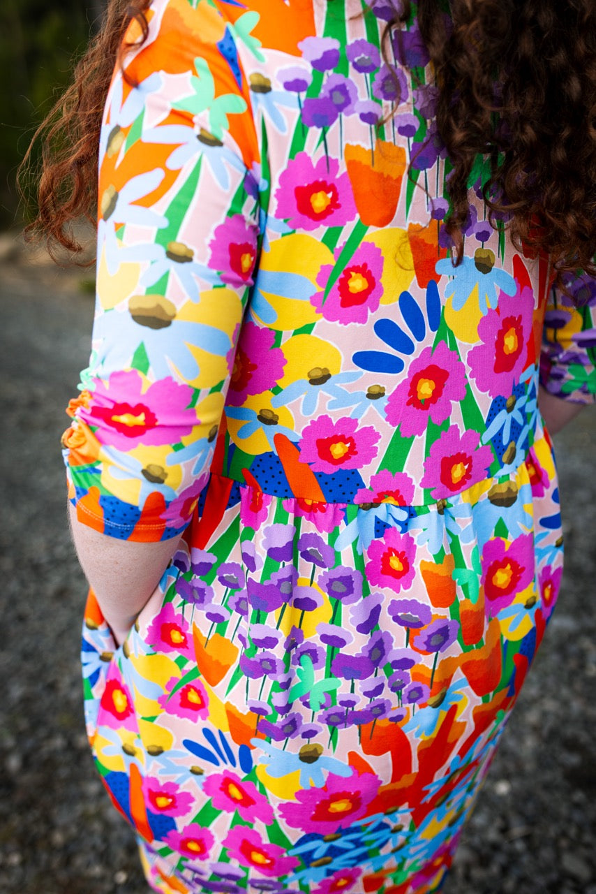 Colorful floral abstract pattern on a garment with a person wearing it. Australian design women’s dress — consciously made, inclusive fit.