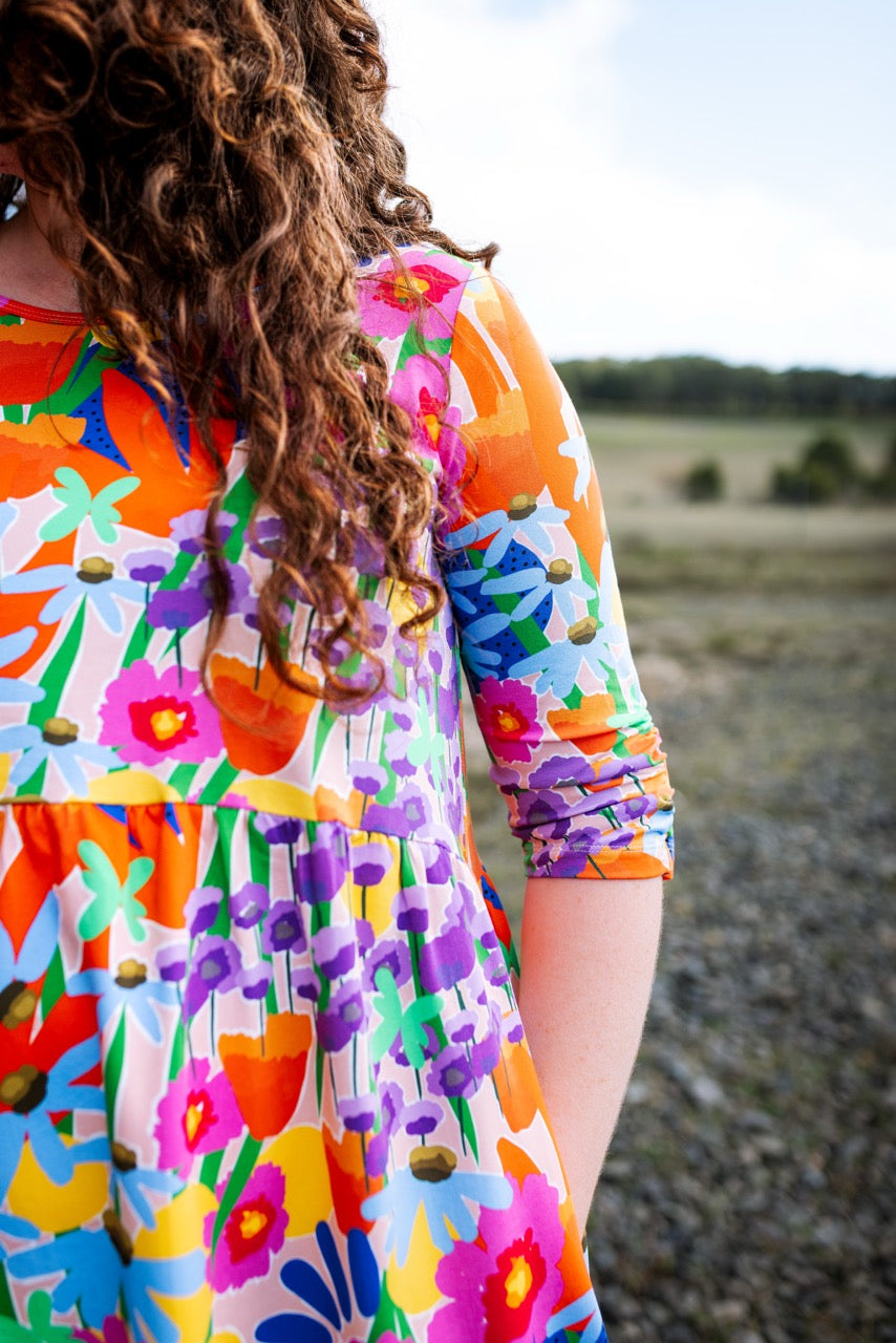 Person wearing a colorful abstract floral dress standing outdoors. Joyful, expressive fashion — FOKE REN dress styled for bold women.
