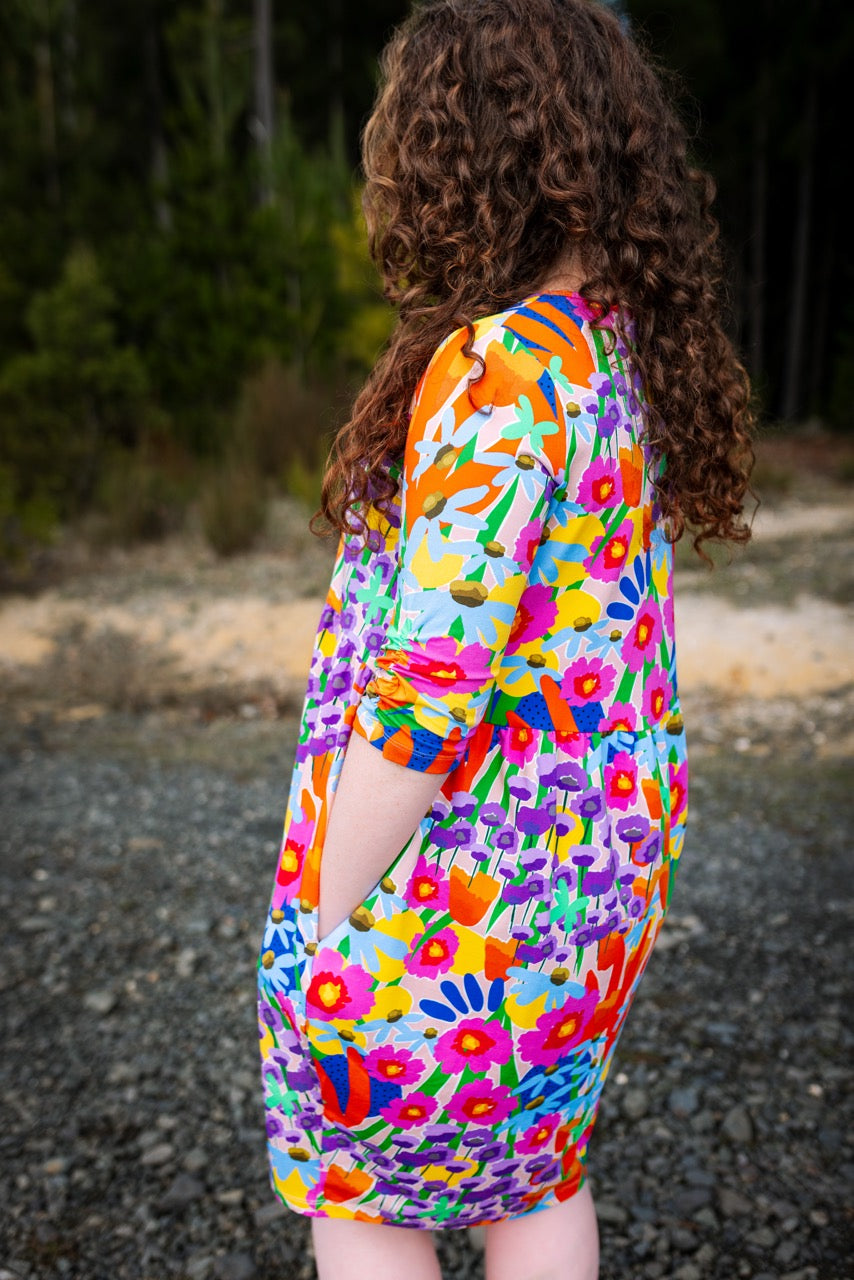 Person wearing a colorful abstract floral dress. Comfortable fabric texture of inclusive women’s dress.