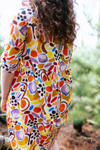 Person wearing a colorful patterned dress in forest. Colourful, playful women’s dress by FOKE, sizes 8–24.