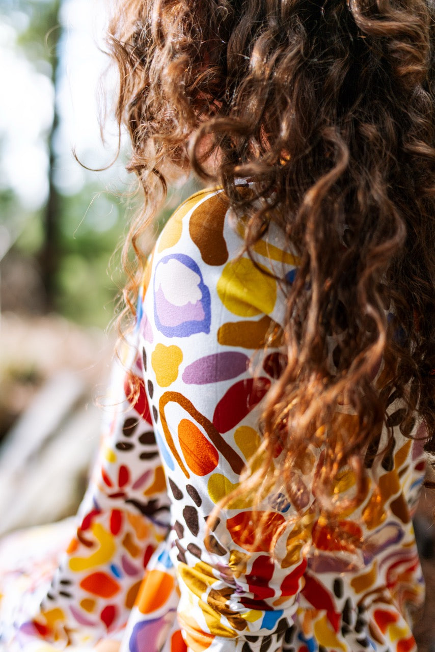 Person wearing a colorful abstract patterned dress natural background. Australian design women’s dress — consciously made, inclusive fit.