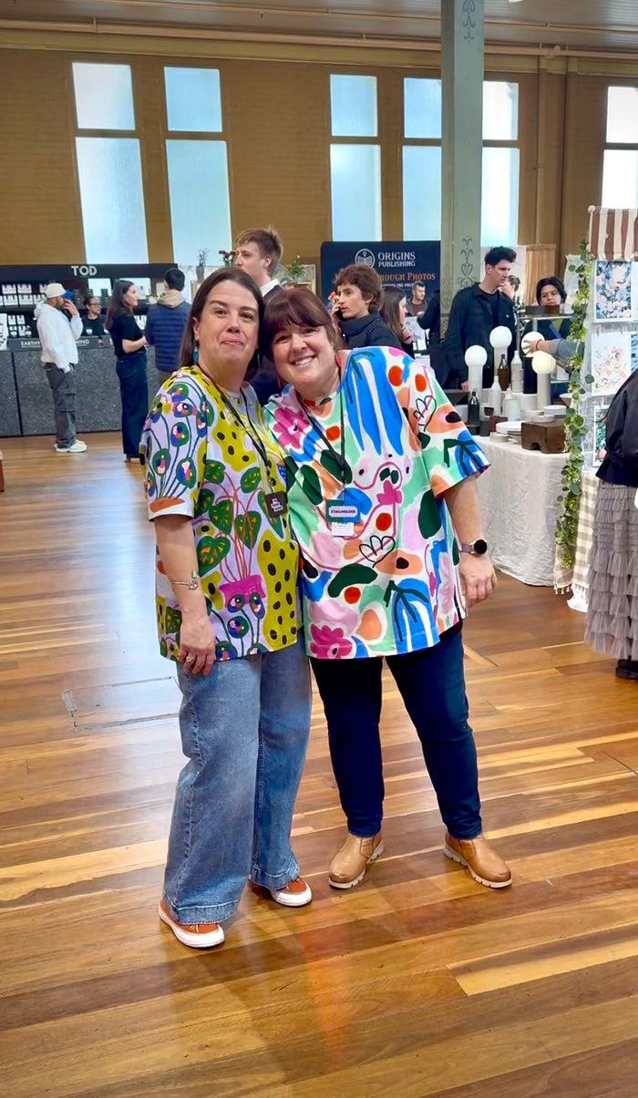 Holly Clinton smiling in a colourful FOKE Hero Tee with a friend at Finders Keepers Market